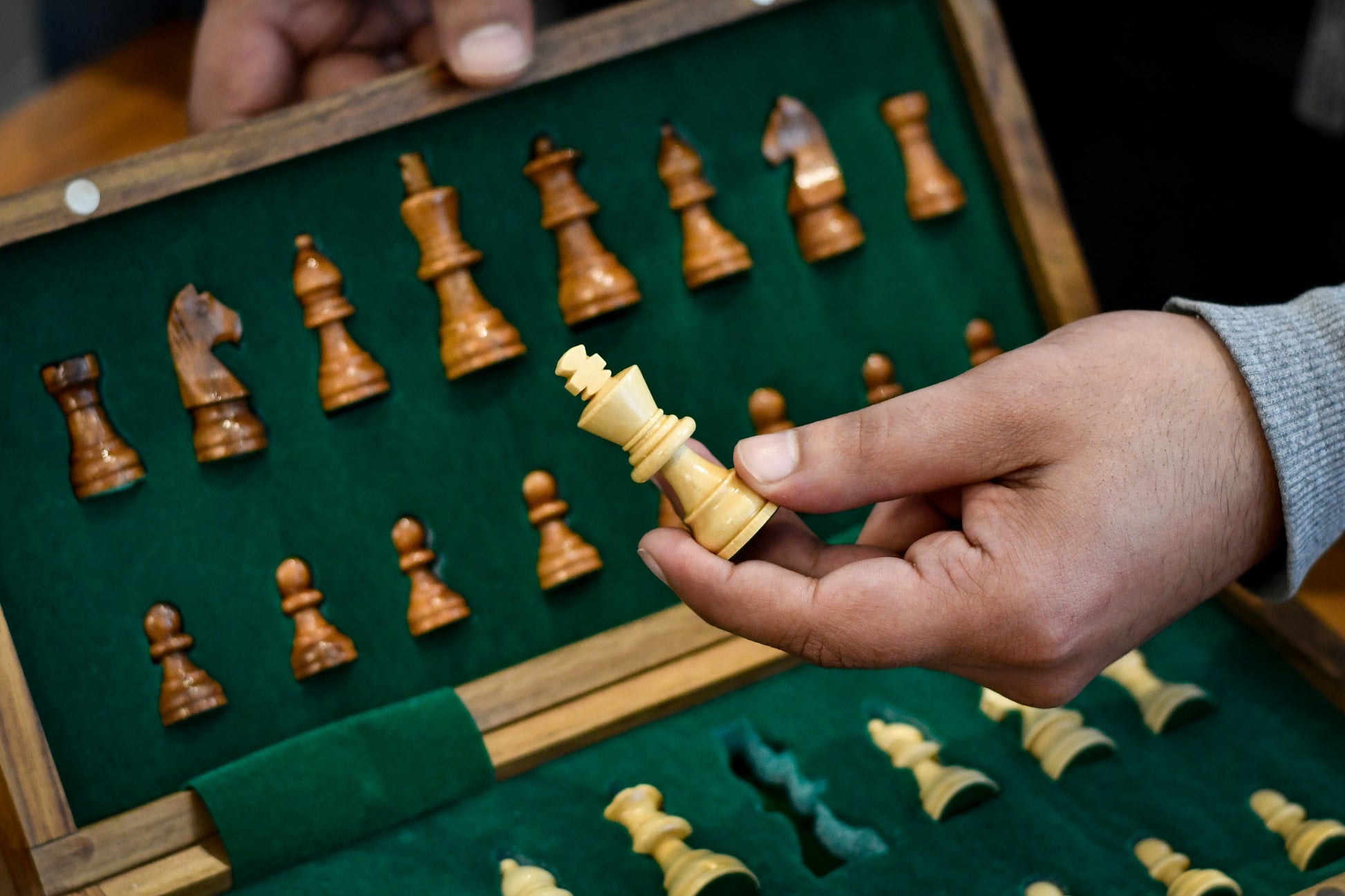 holding travel size queen chess piece made of maple